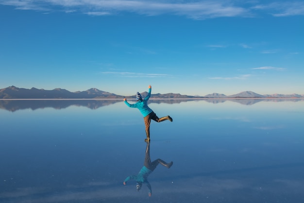 Lever Du Soleil Sur Le Salar D'uyuni En Bolivie Recouverte D'eau, Femme Touriste Sur Le Désert De Sel Et Les Reflets Du Ciel