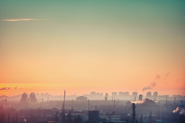 Lever du soleil silhouette, ville européenne de l'industrie avec usine de brume, entrepôt, bâtiment sous le ciel coloré du lever du soleil. Paysage urbain pittoresque avec concept écologique dans des tons doux et chauds. Illustration urbaine étonnante