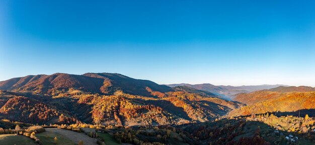 Lever de soleil lumineux à hautes montagnes couvertes de forêt d'automne