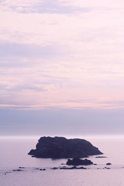 Photo lever de soleil sur la mer avec une île rocheuse au premier plan et l'océan en arrière-plan