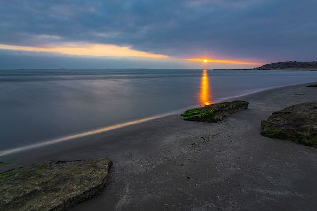 Lever de soleil nuageux sur la côte rocheuse de la mer, longue exposition