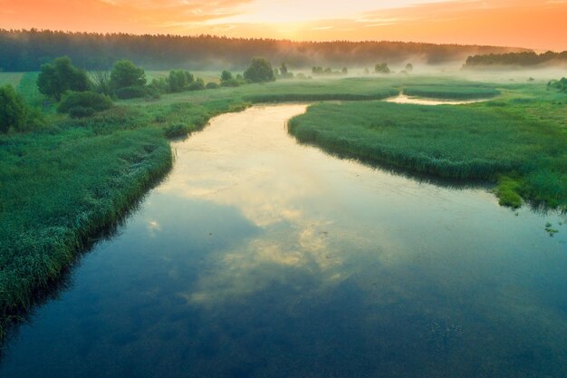 Lever de soleil tôt le matin brumeux sur le lac Paysage rural en été Vue aérienne