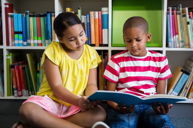 Élèves du primaire lisant un livre à la bibliothèque de l'école