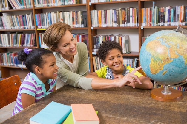 Élèves et enseignant regardant le globe en bibliothèque