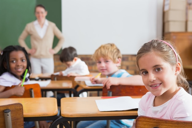 Élèves et enseignant souriant à la caméra dans la salle de classe