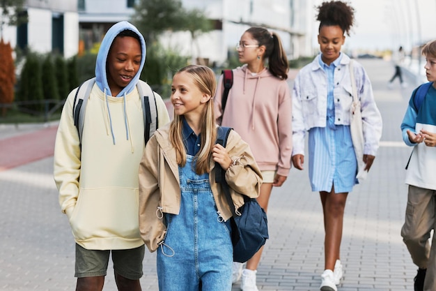 Élèves interculturels mignons avec des sacs à dos discutant sur le chemin du retour