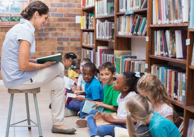 Élèves mignons assis sur le sol dans la bibliothèque