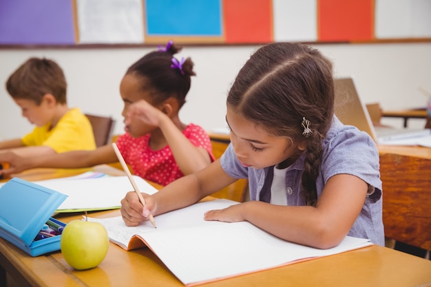 Élèves mignons écrit au bureau dans la salle de classe