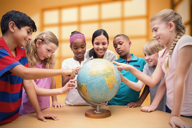 Élèves mignons et enseignant regardant le globe dans la bibliothèque contre la pièce avec une grande fenêtre montrant la ville