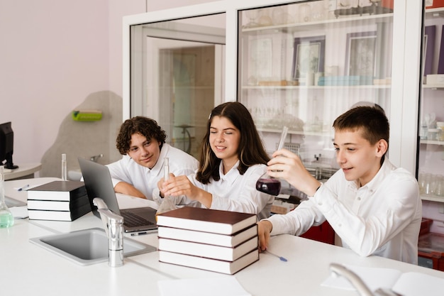 Élèves tenant des flacons avec du liquide pour des expériences en laboratoire Concept d'éducation Groupe d'élèves étudiant la leçon de chimie à l'école