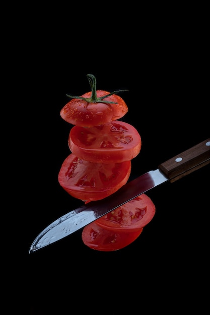 Lévitation de tomates fraîchement coupées. Un couteau coupe la tomate en l'air. tranches de tomates volantes isolés