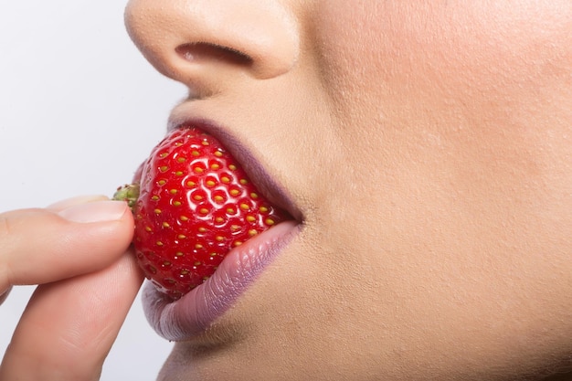 Lèvres femelles mangeant la fraise rouge