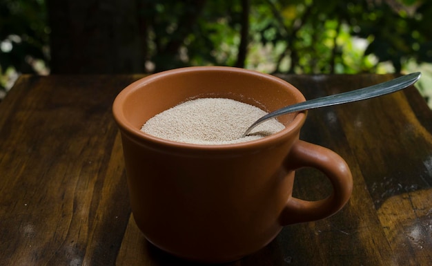 levure en grain séchée dans une tasse d'argile avec une cuillère métallique à l'intérieur