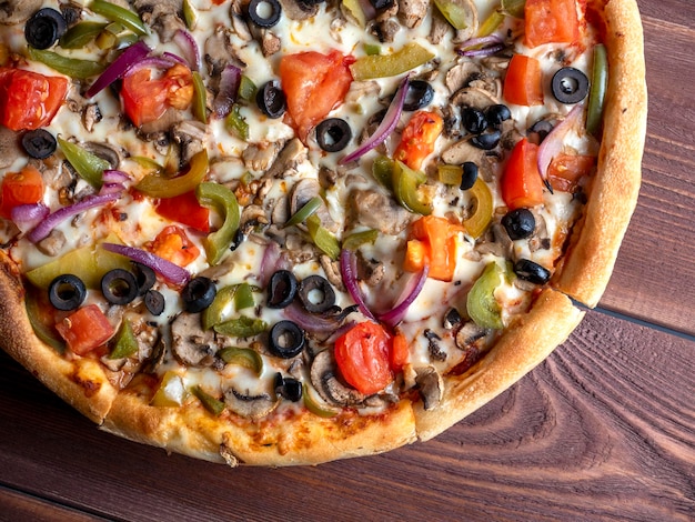 Libre d'une délicieuse pizza végétarienne avec des légumes et des champignons sur un fond de bois marron Vue de dessus mise à plat Aliments malsains