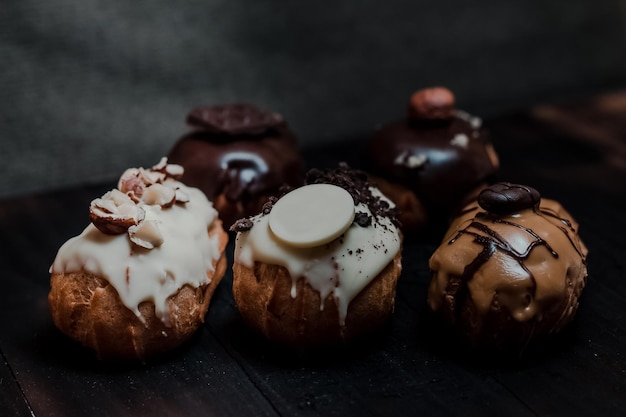 Libre de dessert français traditionnel mini éclairs avec du chocolat blanc et noir et des noix sur un fond sombre