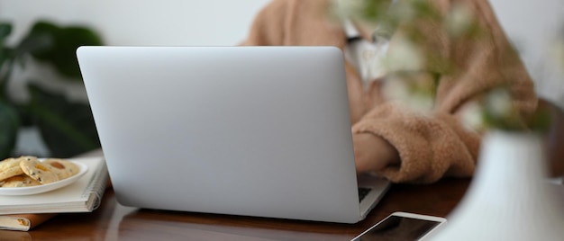 Libre de droit Une femme en chandail marron confortable travaillant sur un ordinateur portable au café