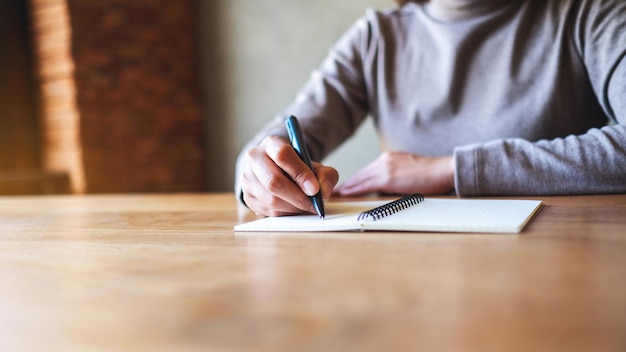 Libre de droit d'une femme écrivant sur un cahier vierge sur la table