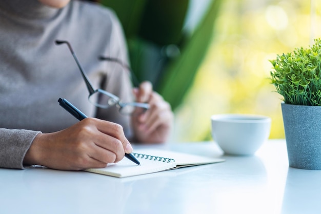 Libre de droit d'une femme écrivant sur un cahier vierge sur la table