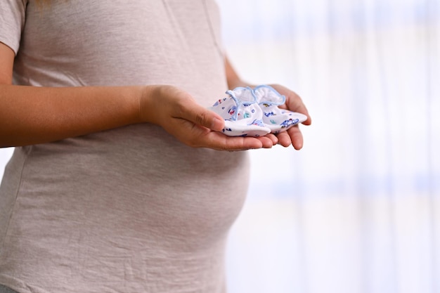 Libre de droit d'une femme enceinte heureuse tenant un bébé nouveau-né chaussettes