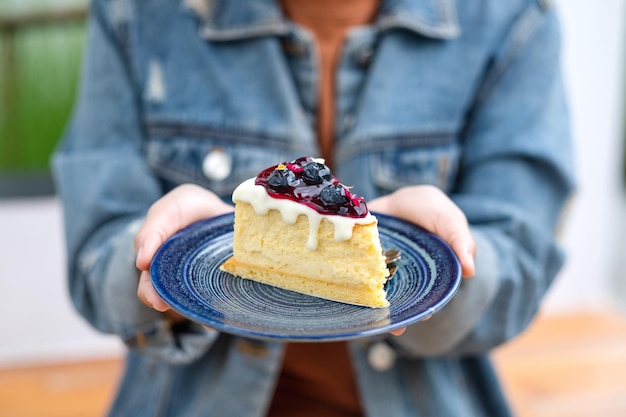 Libre de droit d'une femme tenant et montrant une assiette de cheesecake aux bleuets