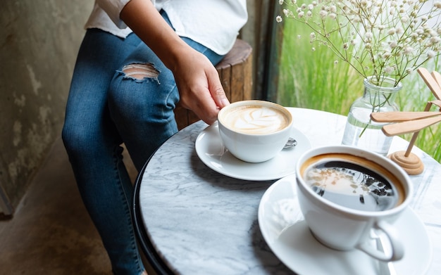 Libre de droit d'une femme tenant une tasse blanche de café chaud sur la table au café