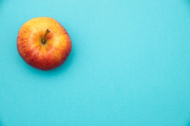 Libre de droit d'une pomme rouge et jaune dans le coin supérieur gauche sur un fond bleu