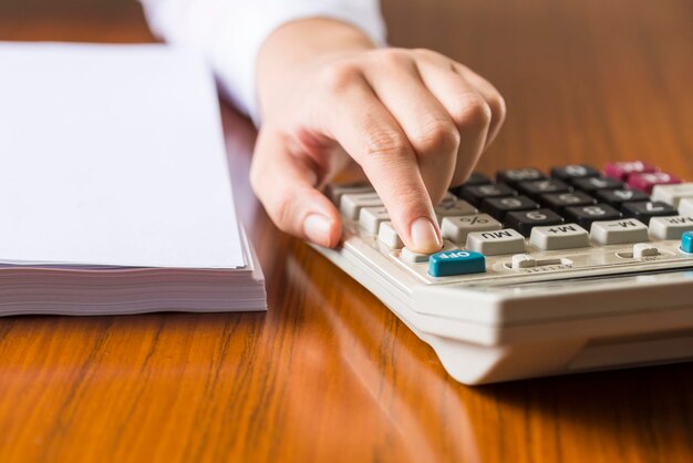 Libre une femme en chemise utilise une calculatrice à son bureau