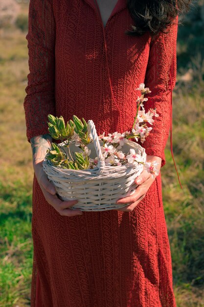 Libre d'une femme tenant un panier blanc avec des fleurs d'amandier