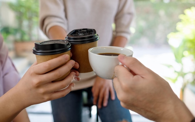 Libre d'un groupe de jeunes a aimé boire et tinter des tasses de café ensemble au café