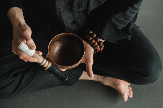 Libre d'un homme dans un kimono noir assis dans une position du lotus et tenant un bol tibétain dans ses mains