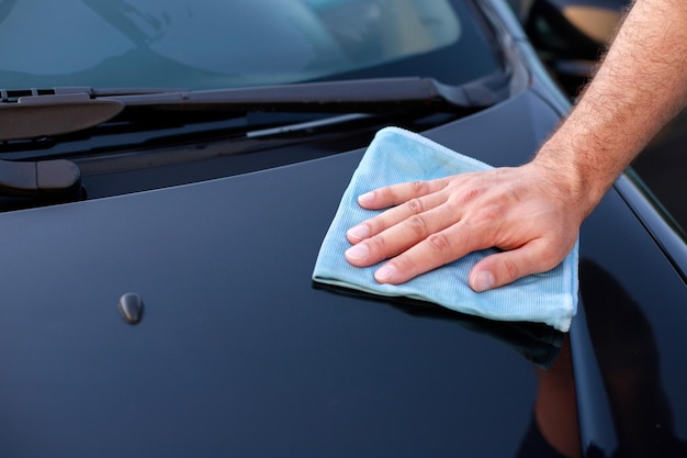 Libre d'un homme frottant le capot d'une voiture avec une serviette à un lave-auto