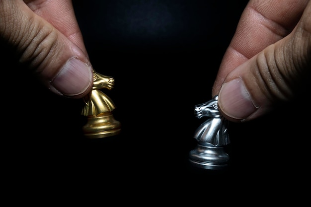 Libre d'un homme tenant un cheval d'échecs d'or et d'argent