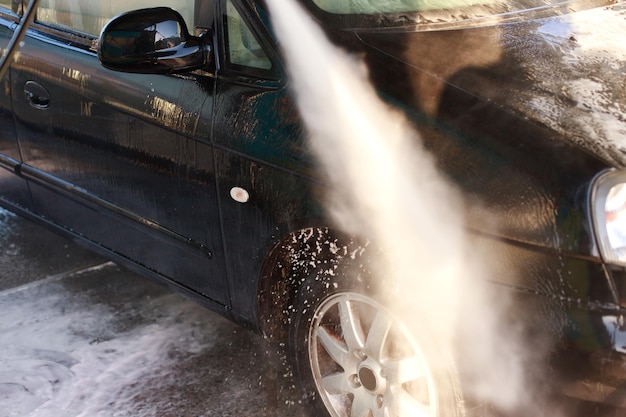 Libre d'un jet d'eau d'un pulvérisateur lave une voiture à un lave-auto en libre-service