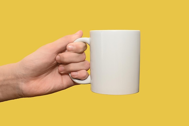 Libre de la main d'une femme tenant une tasse blanche vide sur fond jaune