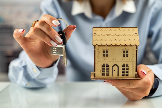 Libre de la main d'un homme protégeant une maison miniature sur une table