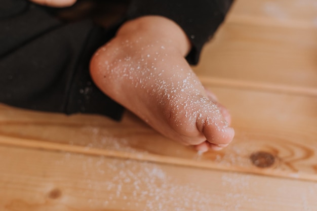 Libre de pieds nus saupoudrés de sucre en poudre assis sur une table en bois d'un enfant. Photo de haute qualité