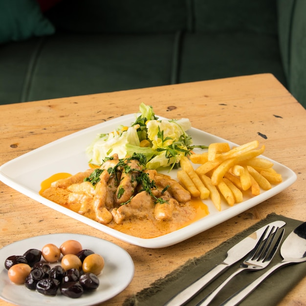 Libre d'un repas avec poulet frites salade et olives sur une table