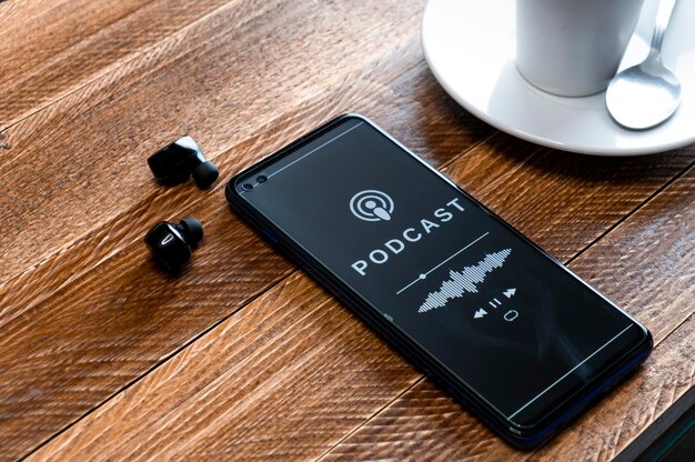 Libre d'un smartphone jouant un podcast avec des écouteurs sur une table de café