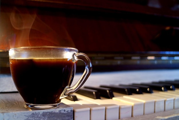 Libre une tasse de café noir chaud avec de la fumée sur le piano