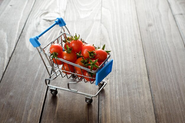 Libre de tomates cerises brillantes rouges dans le panier bleu sur fond de bois foncé