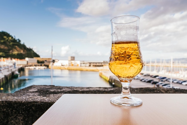 Libre d'un verre de bière sur une table avec le port et les montagnes en arrière-plan