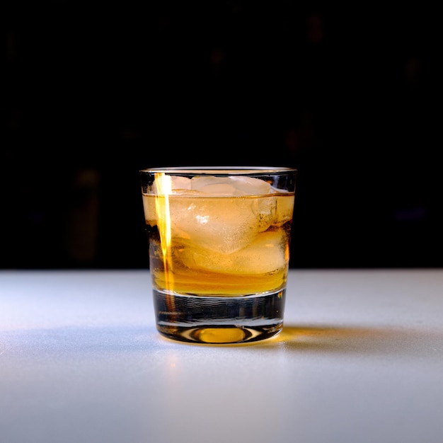 Photo libre d'un verre de whisky glacé froid sur la table sur un fond noir