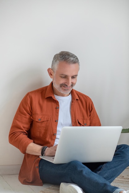 Lié. Bel homme aux cheveux gris travaillant sur un ordinateur portable