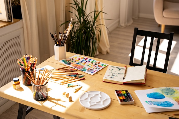 Photo le lieu de travail de l'artiste avec des peintures à l'aquarelle, de la gouache, des pinceaux et des feuilles de papier sur un fond en bois. espace de copie. mise à plat, vue de dessus