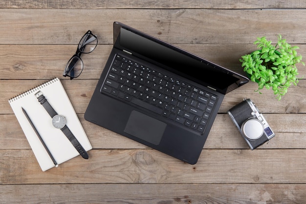 Lieu de travail au-dessus des lunettes et de l'appareil photo du bloc-notes pour ordinateur portable sur le bureau en bois