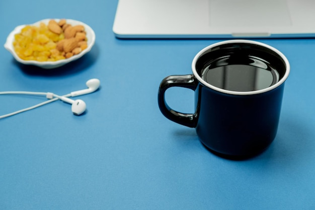 Lieu de travail bleu avec des fruits pour ordinateur portable et une tasse de thé noir