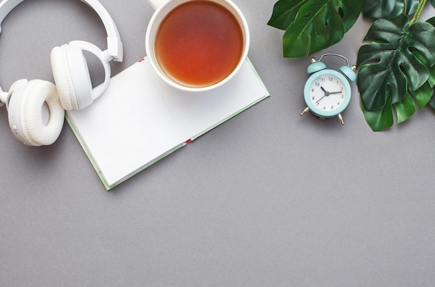 Lieu de travail avec un bloc-notes casque une tasse de thé ou de café réveil et plante verte