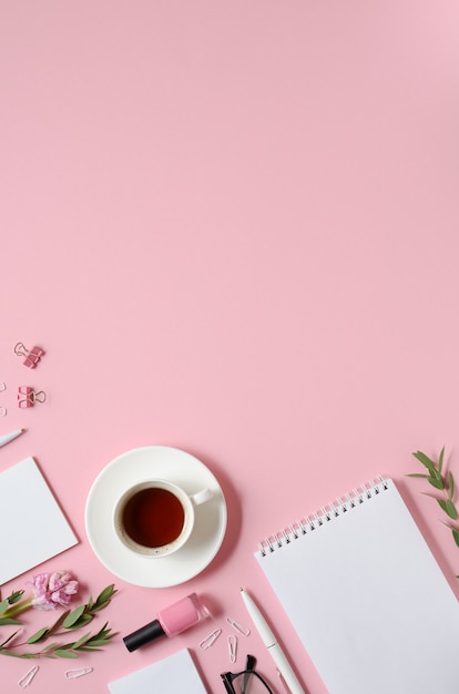 Photo lieu de travail avec bloc-notes, stylo, tasse à café et autres accessoires sur fond rose avec espace copie