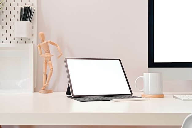 Lieu de travail de bureau moderne avec maquette de tablette écran blanc, pc et fournitures élégantes