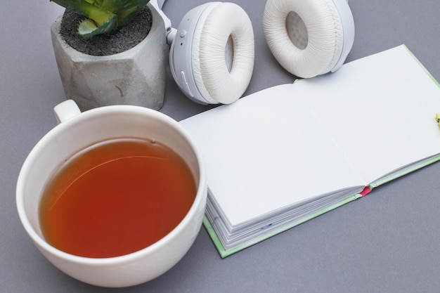 Lieu de travail avec un casque de bloc-notes tasse de thé ou de café et plante verte